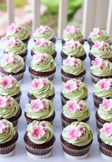 Cupcakes with green icing and pink flowers.