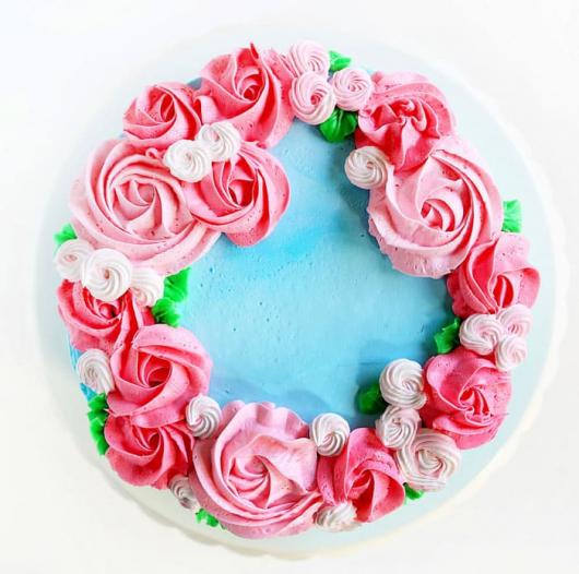 Amazing cake with blue whipped cream topping and pink flowers in different shades