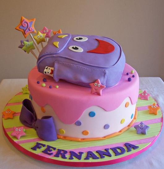 Adventurous Dora cake with purple backpack on top.