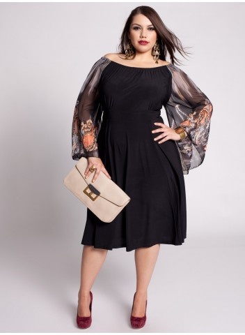 Model wears black dress with transparencies and nude bag.