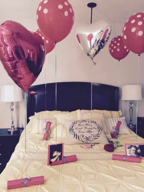 bed decorated with balloons, letters and photos