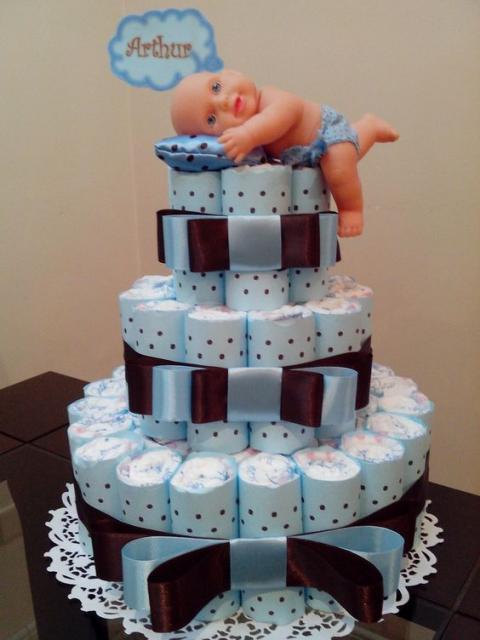 male fake cake with larger bows, blue polka dot print and a doll lying on a pillow on top