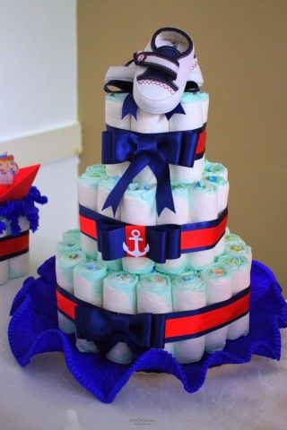 masculine fake cake with blue bows, blue and red ribbon, sailor symbol and a pair of baby shoes on top