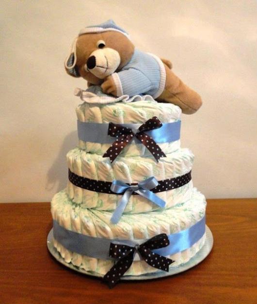 male fake cake with bows printed with blue polka dots and a single blue one, it has a teddy bear on top