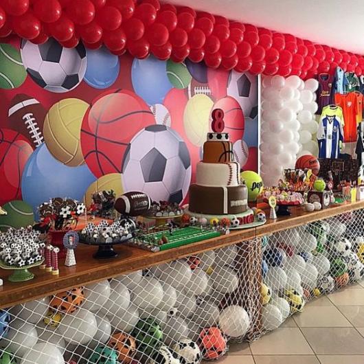 Children's party about various sports, with balls under the cake table.