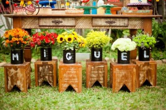 Front of cake table decorated with flower pots with letters forming the birthday boy's name.
