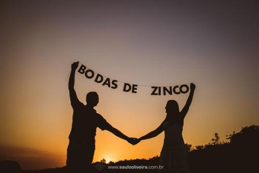 Couple holding letters that form the sentence " zinc wedding".